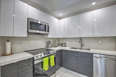 a kitchen with white cabinets and stainless steel appliances at Canal-Front Condo Walk to Downtown Ft Lauderdale! in Fort Lauderdale