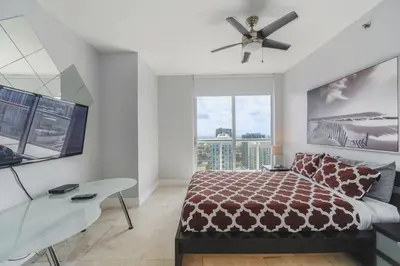 a bedroom with a bed and a desk and a window at Wonderful 2/2 Condo at Icon Brickell With Pool in Miami