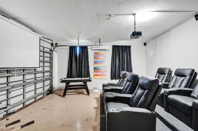 a room with chairs and a screen and a projector at Spacious home wprivate pool game room in Plantation
