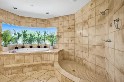 a bathroom with a tub and a window with palm trees at Spacious home wprivate pool game room in Plantation