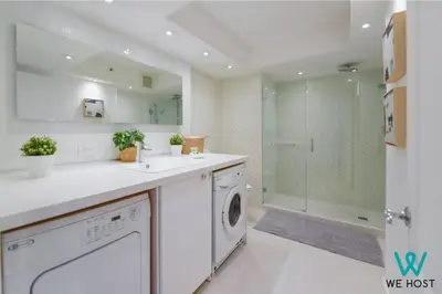 a white bathroom with a washing machine and a shower at Wonderful Condo in Brickell With Pool and Gym in Miami