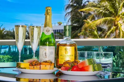 a bottle of champagne and fruit on a table with glasses at Hollywood Beachfront Condo, Steps to Ocean, Pool & Game Room in Hollywood