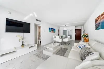 a living room with a white couch and a tv at Hollywood Beach Ocean View Condo, Direct Beach Access, Pool & Resort Amenities in Hollywood