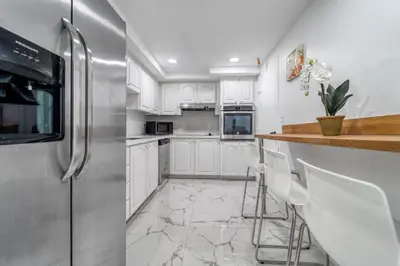 a kitchen with white cabinets and a stainless steel refrigerator at Hollywood Beach Ocean View Condo, Direct Beach Access, Pool & Resort Amenities in Hollywood