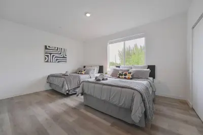 two beds in a bedroom with white walls and wood floors at Amazing Townhouse 15 minutes from the Beach in Miami