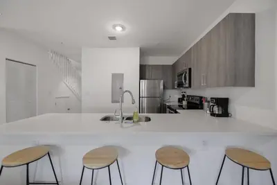a kitchen with three bar stools and a counter top at Amazing Townhouse 15 minutes from the Beach in Miami