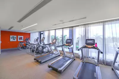 a gym with a row of treadmills and exercise bikes at Modern Hotel with Pool & Gym in Prime Doral Location in Miami