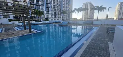 a large blue swimming pool with palm trees and buildings at Modern Hotel with Pool & Gym in Prime Doral Location in Miami
