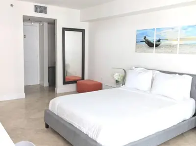 a white bedroom with a large bed and a mirror at Condo in Brickell Business District in Miami