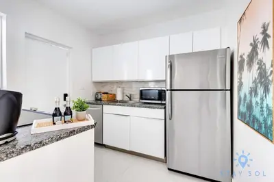 a white kitchen with a stainless steel refrigerator at Free Parking, Bay View, Pool, Step To Beach in Hollywood
