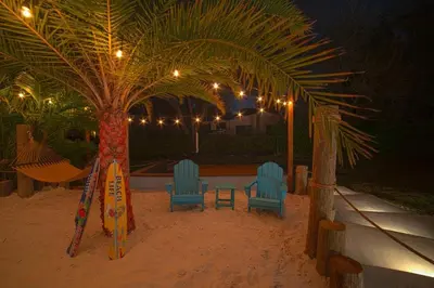 two chairs and a table in the sand under a palm tree at Heated pool in a Precious House close to Zoo Parks and Arts in Cutler Bay