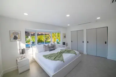 a white bedroom with a large bed and a window at Heated pool in a Precious House close to Zoo Parks and Arts in Cutler Bay