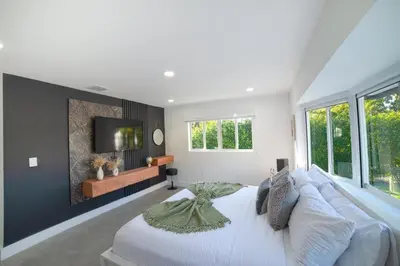 a bedroom with a white bed and a tv on a wall at Heated pool in a Precious House close to Zoo Parks and Arts in Cutler Bay