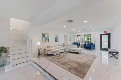 a living room with white furniture and a staircase at Waterfront Retreat: 7BR Villa with Pool Firepit in Fort Lauderdale