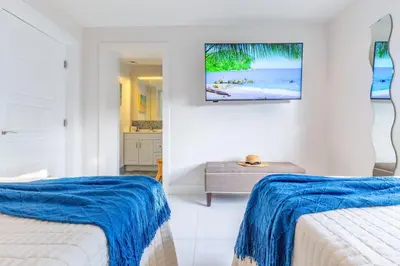 a white room with two beds and a table at Fun Family-Friendly Poolside Escape Near Beach in Dania Beach