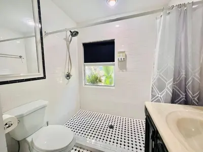 a bathroom with a toilet and a sink and a window at Fun Family-Friendly Poolside Escape Near Beach in Dania Beach
