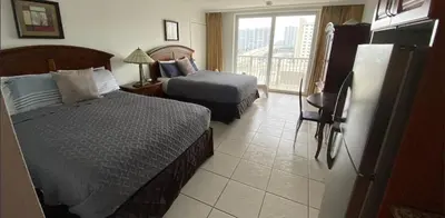 a hotel room with two beds and a balcony at Ramada Marco Polo Beach in Miami Beach