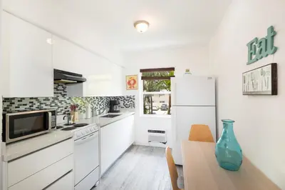 a white kitchen with a table and a refrigerator at The Oasis in Miami