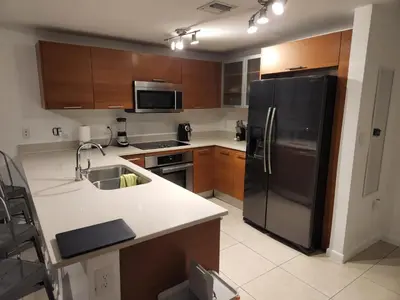 a kitchen with a black refrigerator and wooden cabinets at Wonderful 1 bedroom condo in Midtown. in Miami