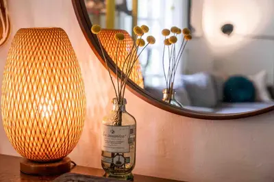 a bottle with flowers in it next to a lamp and a mirror at Cozy Room near Miami Airport in Miami