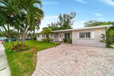 a white house with a palm tree and a driveway at Pool House on the Water 2 in Miami