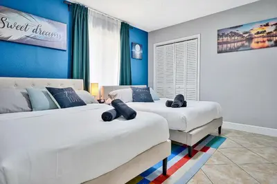two beds in a bedroom with blue walls at Vacay Spot Gables 4 to 23 Guest GameRoom 2 Kitchens 2 BBQ, 2 BAR, Backyard, Patio, Prime LOC! 6 blocks away from Bars, Nite Clubs, Res, Shops in Miami