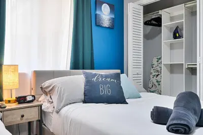 a bedroom with a bed with a blue wall at Vacay Spot Gables 4 to 23 Guest GameRoom 2 Kitchens 2 BBQ, 2 BAR, Backyard, Patio, Prime LOC! 6 blocks away from Bars, Nite Clubs, Res, Shops in Miami