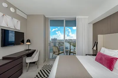a bedroom with a bed and a desk and a large window at Wrap Around Balcony - 2Br - Amazing Views - Pools in Hollywood
