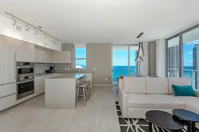 a living room with a white couch and a kitchen at Wrap Around Balcony - 2Br - Amazing Views - Pools in Hollywood