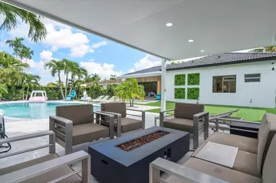 a patio with chairs and a swimming pool at VillaLee-Jungle Palm Island white marble pool Area in Miami