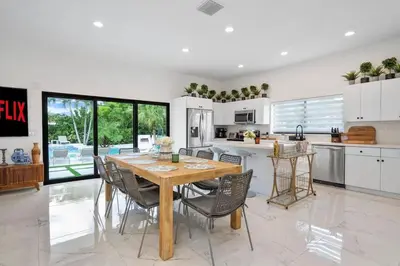 a kitchen with a wooden table and chairs at VillaLee-Jungle Palm Island white marble pool Area in Miami