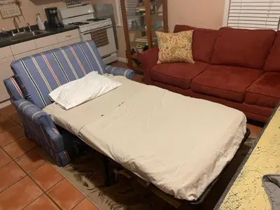 a bed in a living room next to a couch at Key West Style Historic Home in Coconut Grove Florida, The Blue House in Miami