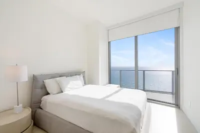 a white bedroom with a large bed and a large window at Zen Luxury Resort Ocean Front Penthouse in Hollywood
