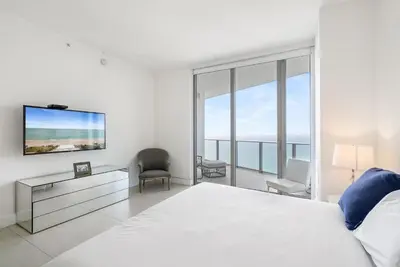 a white bedroom with a large bed and a tv at Zen Luxury Resort Ocean Front Penthouse in Hollywood