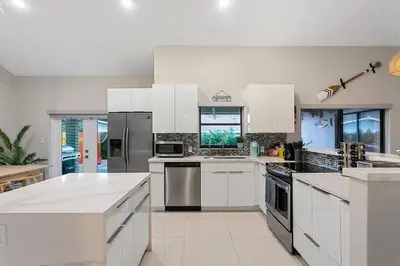 a large kitchen with white cabinets and stainless steel appliances at Citrus+Sunshine/Heated Pool/6 min to Beach/Casino in Dania Beach