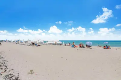 a group of people sitting on a beach with umbrellas at Zen Vacation Rentals Ocean Front at Lyfe Resort in Hollywood