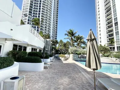 an umbrella next to a swimming pool with buildings at Trump International Resort by Zen Vacation Rentals in Miami Beach
