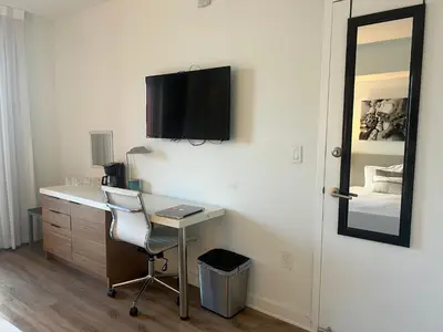a room with a desk and a television on a wall at BeachWalk Studio Steps from the Sand 2 Full Beds 805 B in Hallandale Beach
