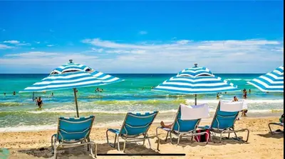 a group of chairs and umbrellas on a beach at BeachWalk Studio Steps from the Sand 2 Full Beds 805 B in Hallandale Beach