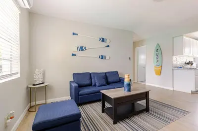a living room with a blue couch and a table at Luxury House with Delightful Beach Style! in Dania Beach