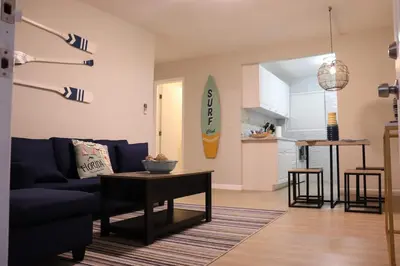 a living room with a blue couch and a surfboard on the wall at Luxury House with Delightful Beach Style! in Dania Beach