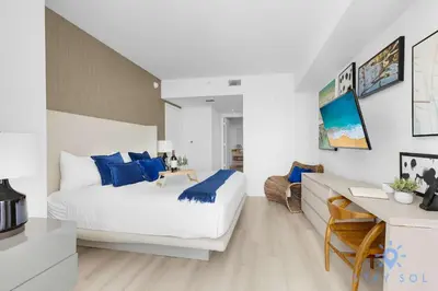 a bedroom with a bed with blue pillows and a desk at Insane Ocean View Balcony - Beachfront Condo - Pool in Hollywood