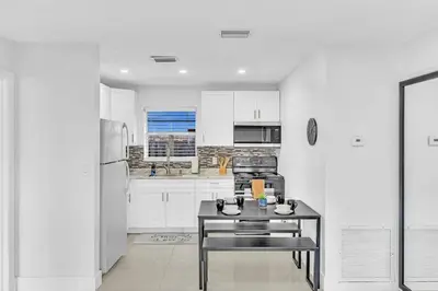 a white kitchen with a table and a refrigerator at Beach And Hard Rock Hollywood Vacation House Ha02 in Hollywood