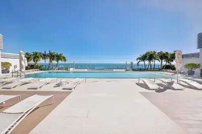 a swimming pool with lounge chairs and the ocean at Monte Carlo by Miami Vacations in Miami Beach