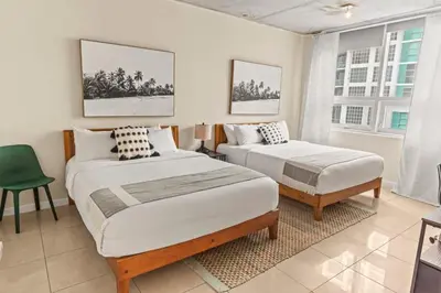 a bedroom with two beds and a green chair at Urban Retreat - Location Pool Gym & Parking in Miami