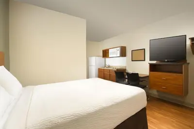 a hotel room with a bed and a flat screen tv at Extended Stay America Select Suites - Fort Lauderdale - Airport - West in Davie