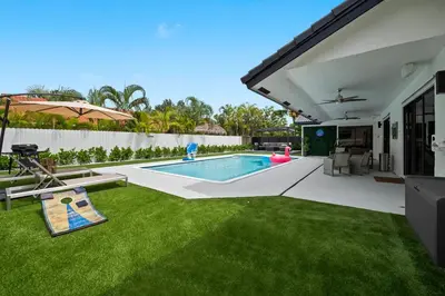 a backyard with a swimming pool and green grass at Villa Paradise Miami, Luxury Gem with Heated Pool, Game Room, Fire Pit, 3 Bed 2 Bath in Miami