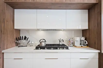 a kitchen with white cabinets and a stove top oven at Villa Paradise Miami, Luxury Gem with Heated Pool, Game Room, Fire Pit, 3 Bed 2 Bath in Miami