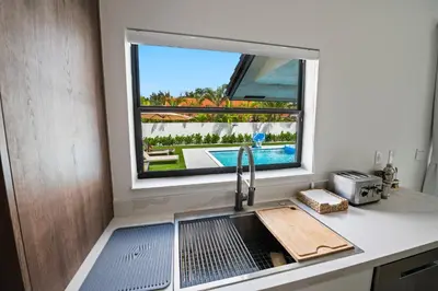a kitchen with a sink and a window with a pool at Villa Paradise Miami, Luxury Gem with Heated Pool, Game Room, Fire Pit, 3 Bed 2 Bath in Miami