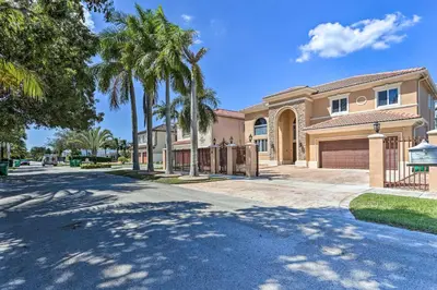 a house with palm trees in front of a driveway at Spacious Miami Retreat with Grill, Pool and Dock! in Miami